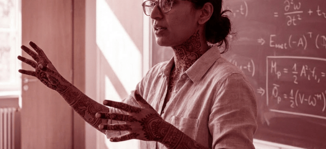 Woman with henna tattoos on arms and neck teaching math in classroom